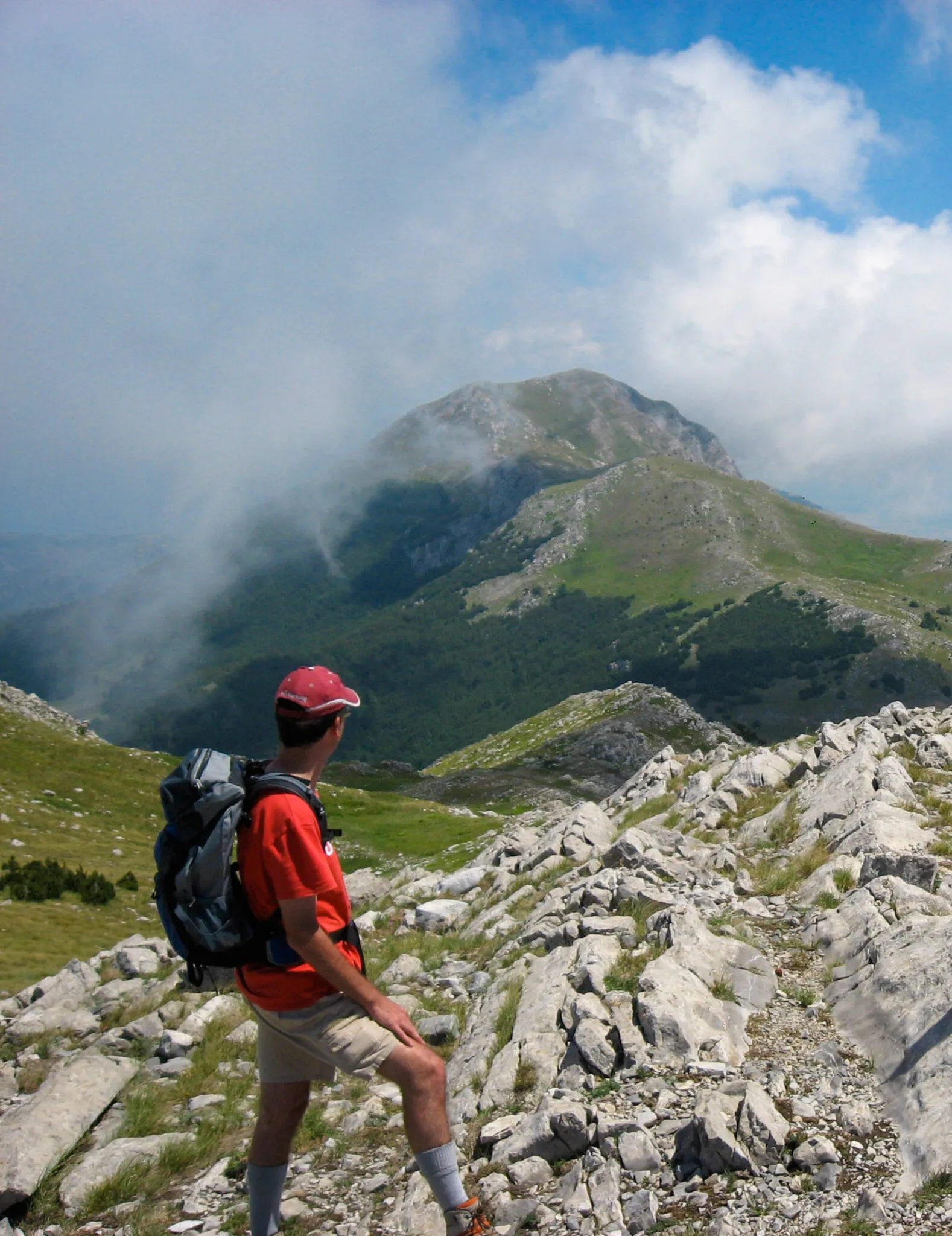 A man pauses during a hike to look at the mountains