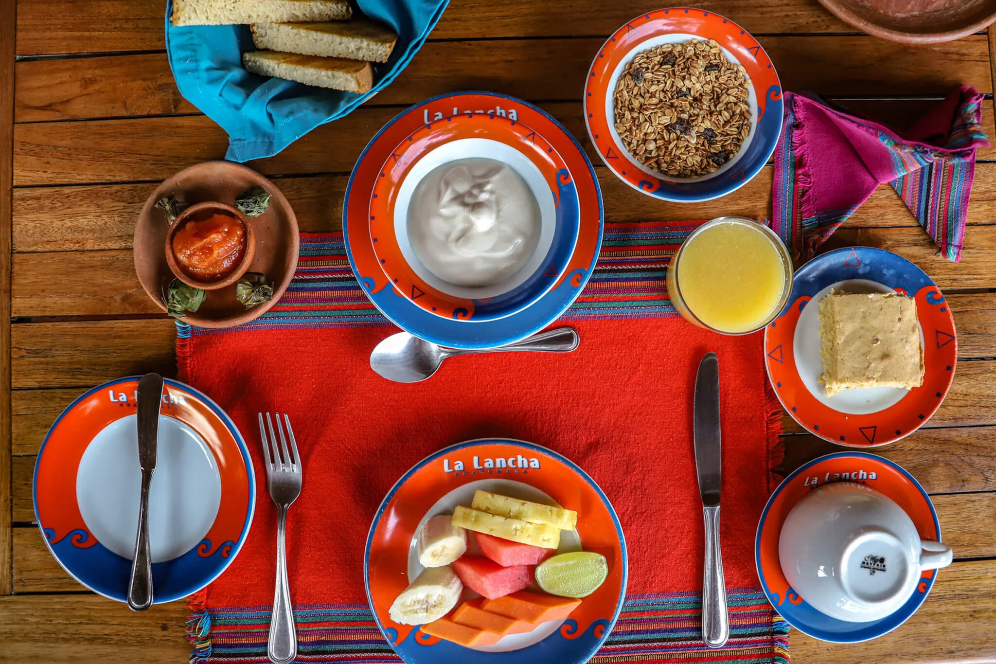 A breakfast spread from the restaurant at La Lancha, including fruit, yogurt, orange juice, and toast.