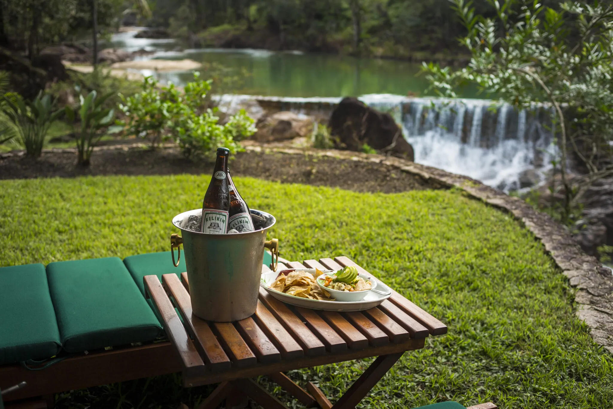 A bench and table with cold drinks and ceviche near a waterfall