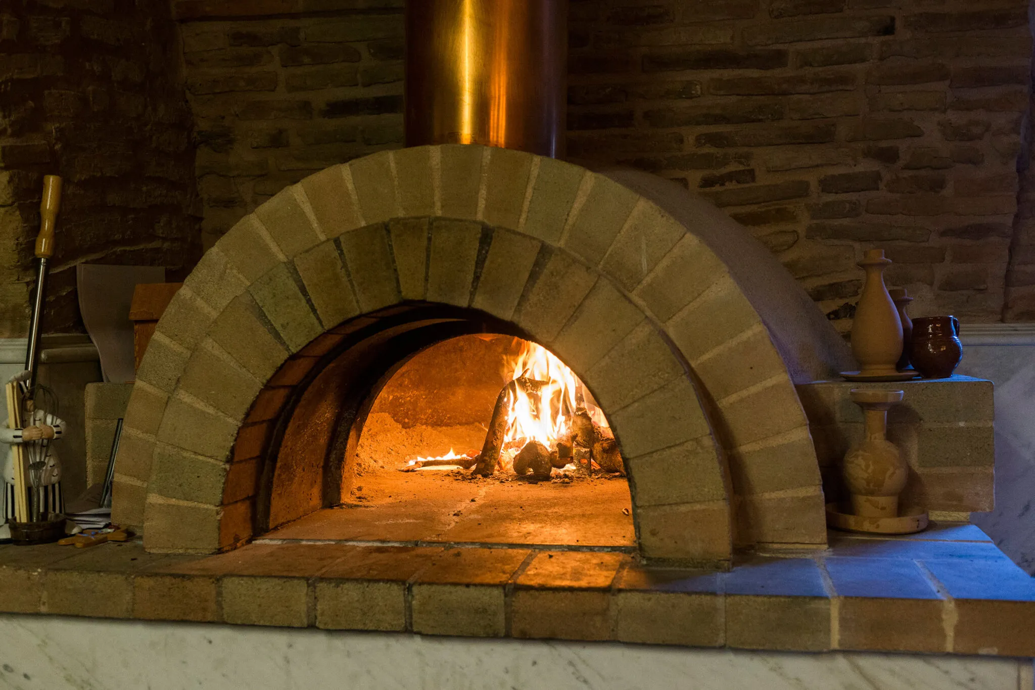 A fire blazes in a brick oven