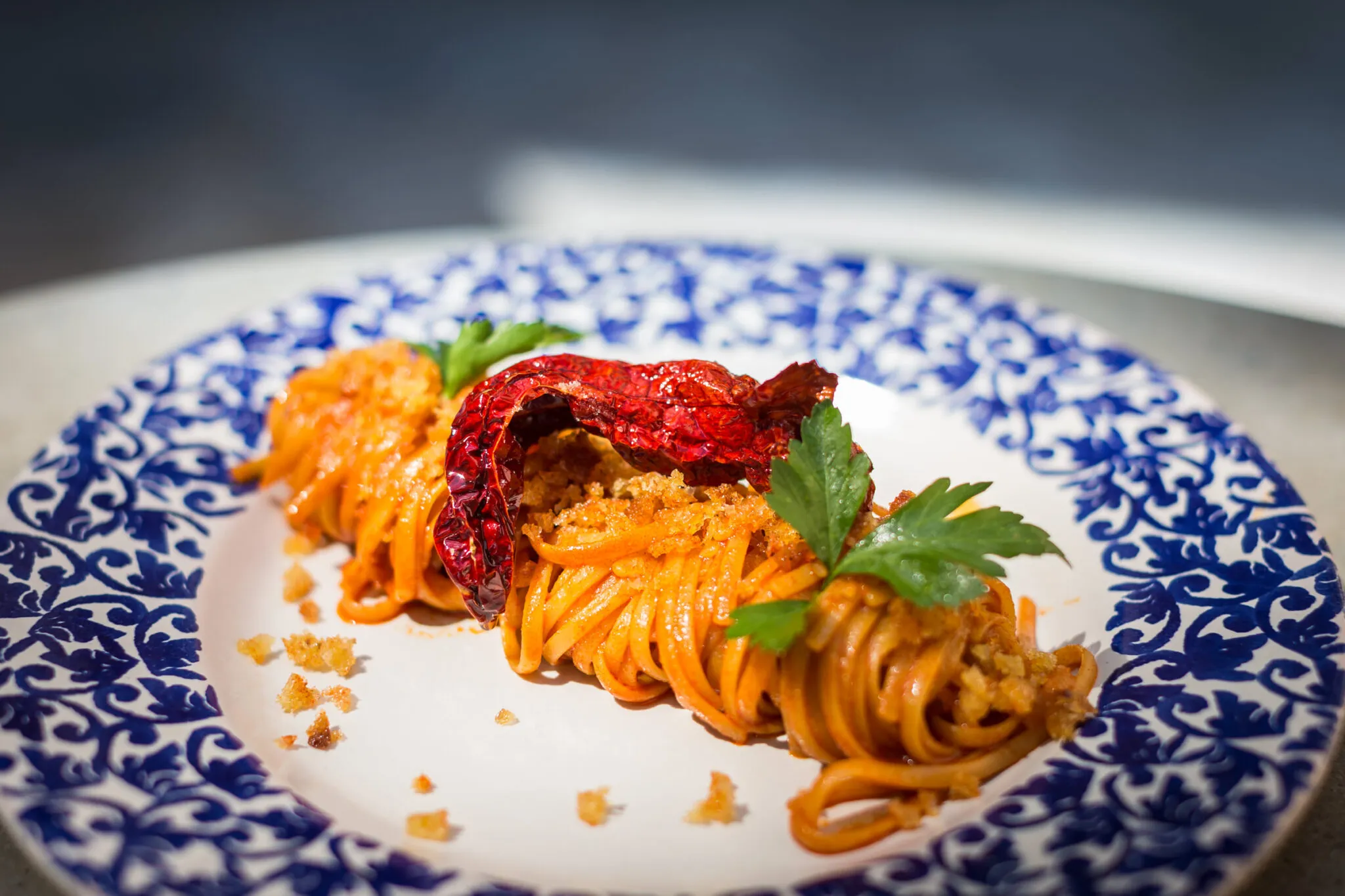 A plate of pasta topped with a dried chili pepper