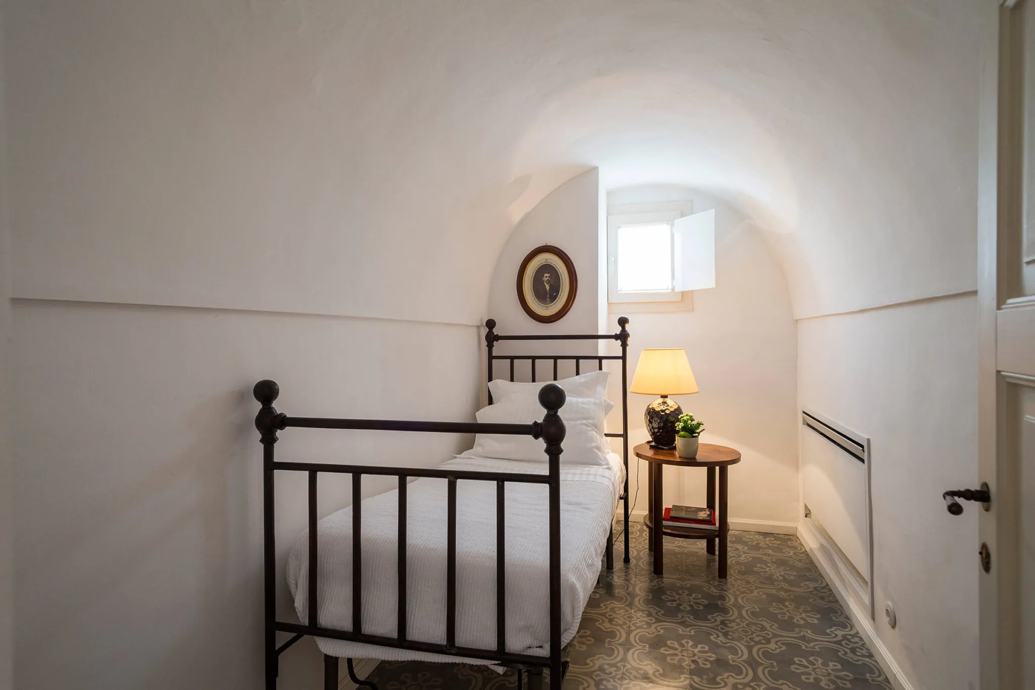 Upstairs bedroom with single bed under an arched white ceiling