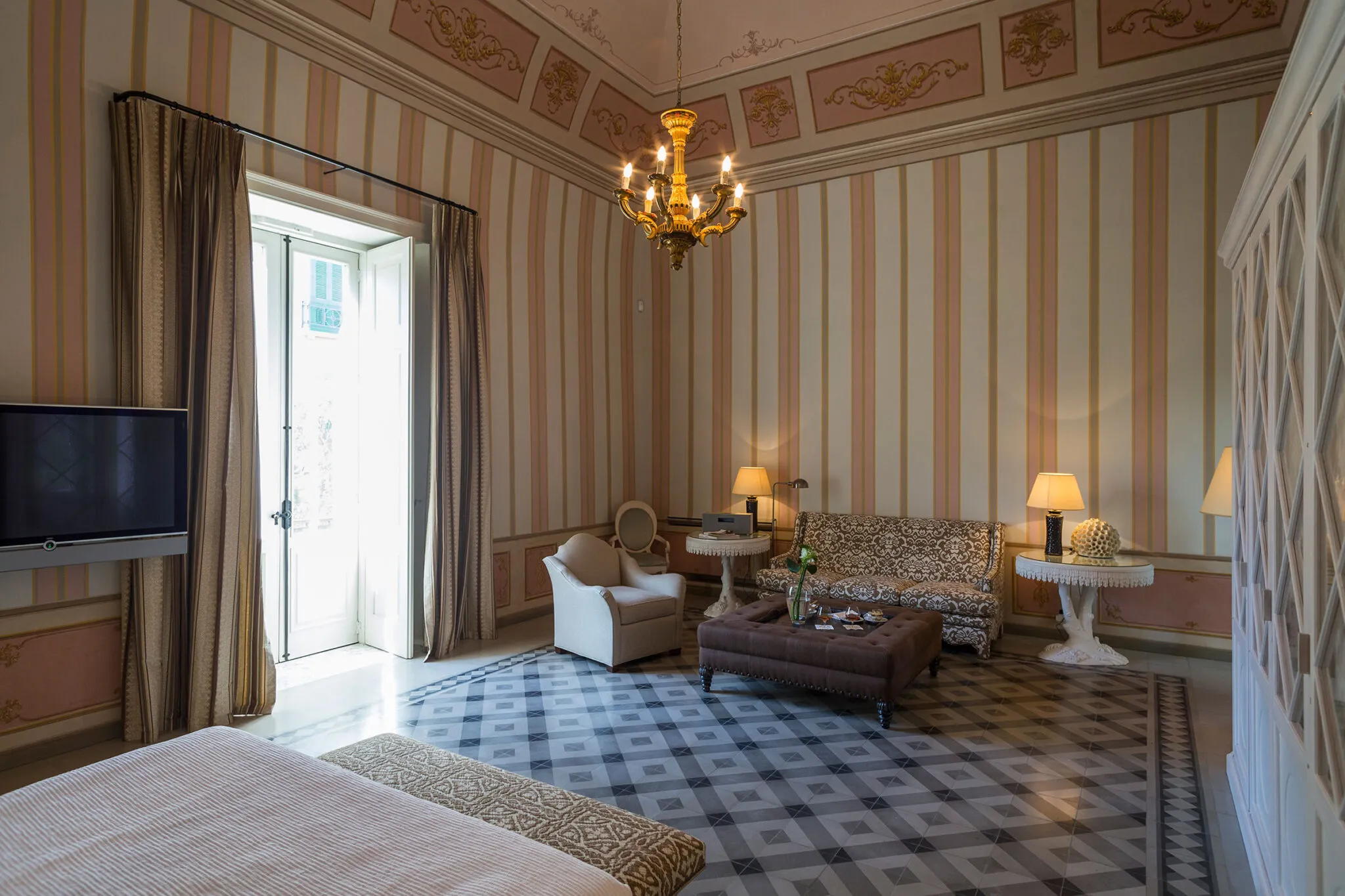 Sitting area with couch, chair and ottoman against striped wallpaper