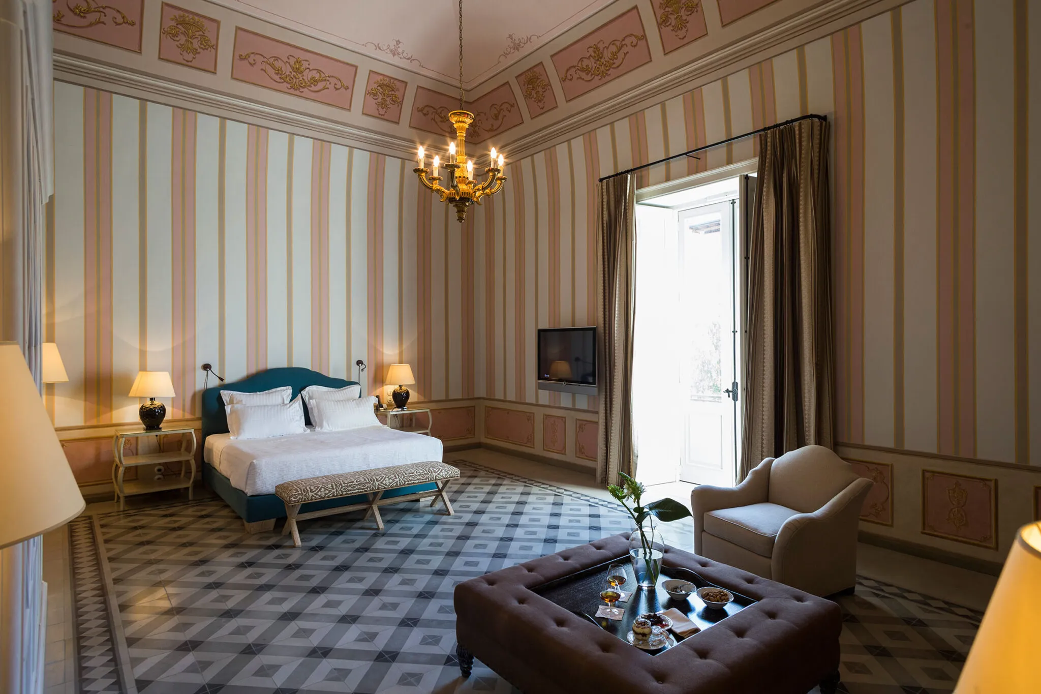 Suite bedroom with a double bed, tiled floor, striped wallpaper and large windows