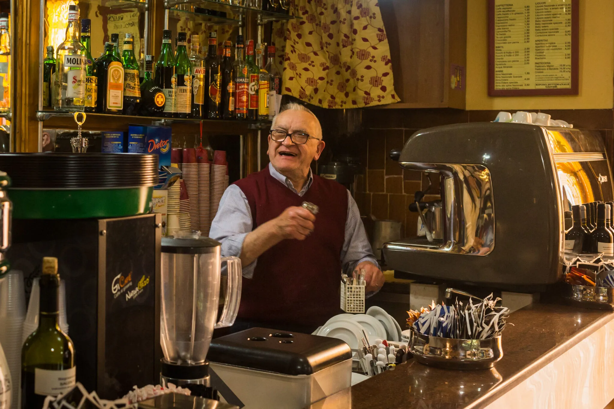 A smiling man behind an espresso machine