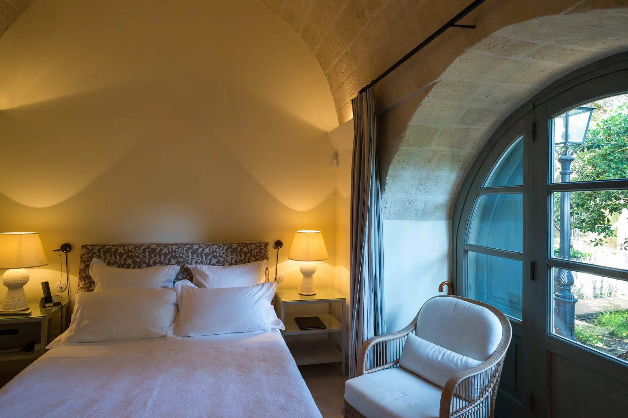 A double bed next to an arched window