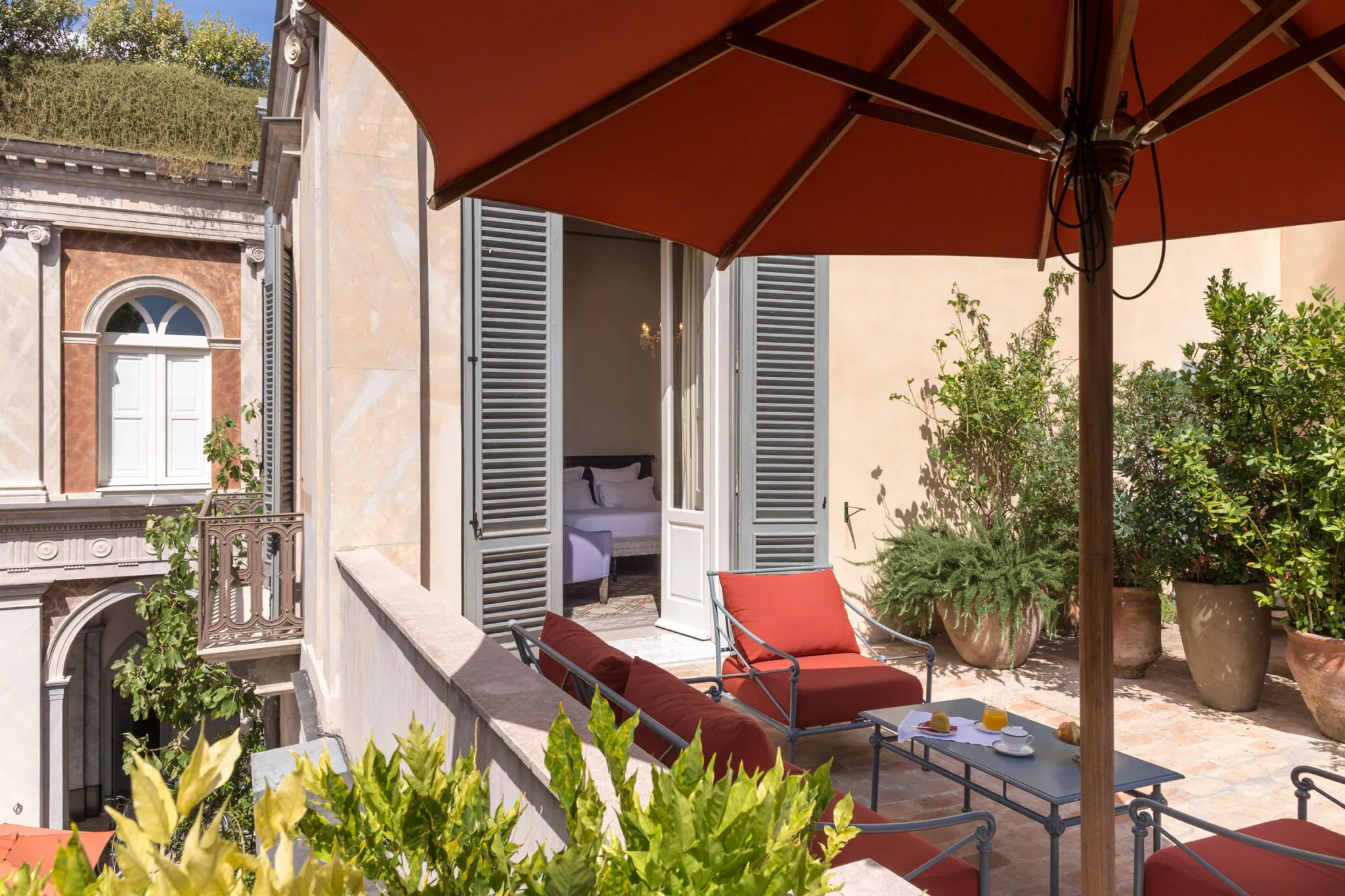 Balcony seating area with red cushioned chairs, table and umbrella