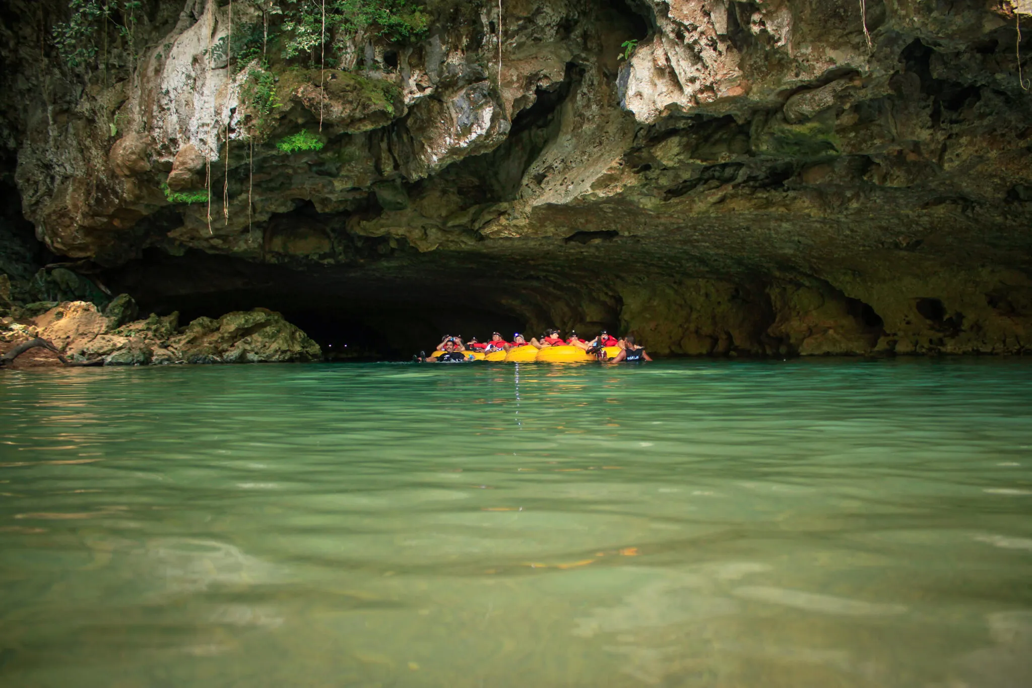 People in inner tubes at the mouth of a cave