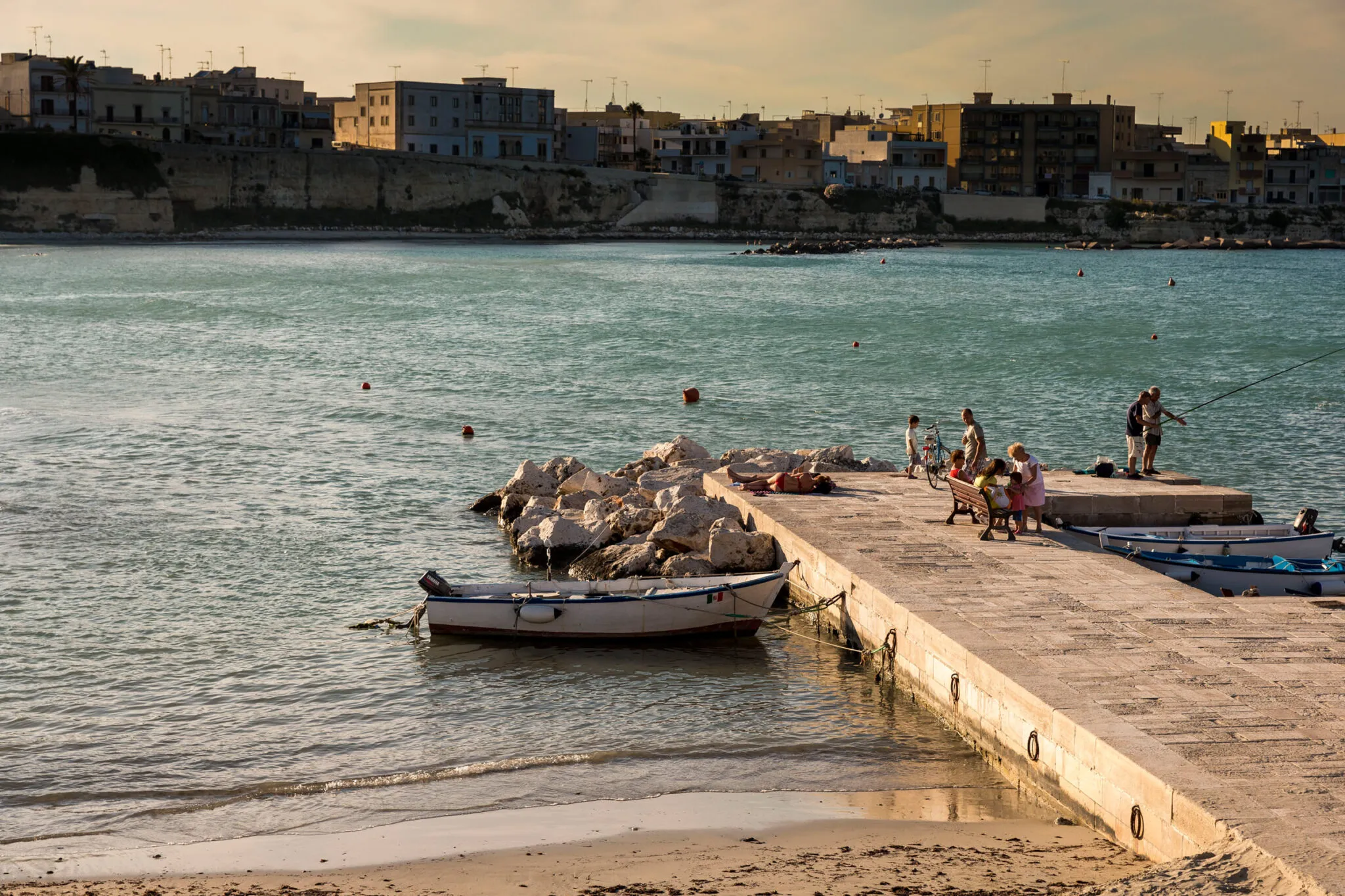 People on a stone pier with docked boats