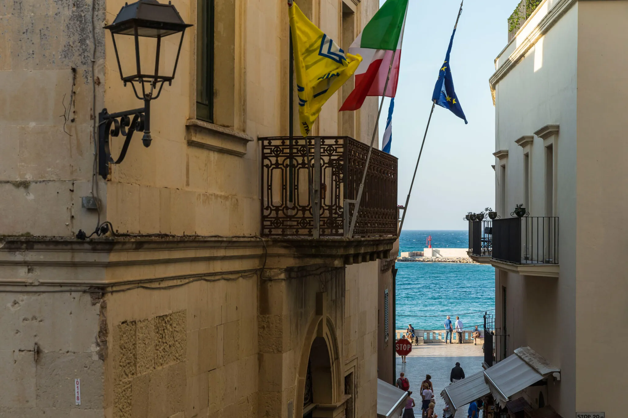 Flags fly from a balcony with a view of the sea