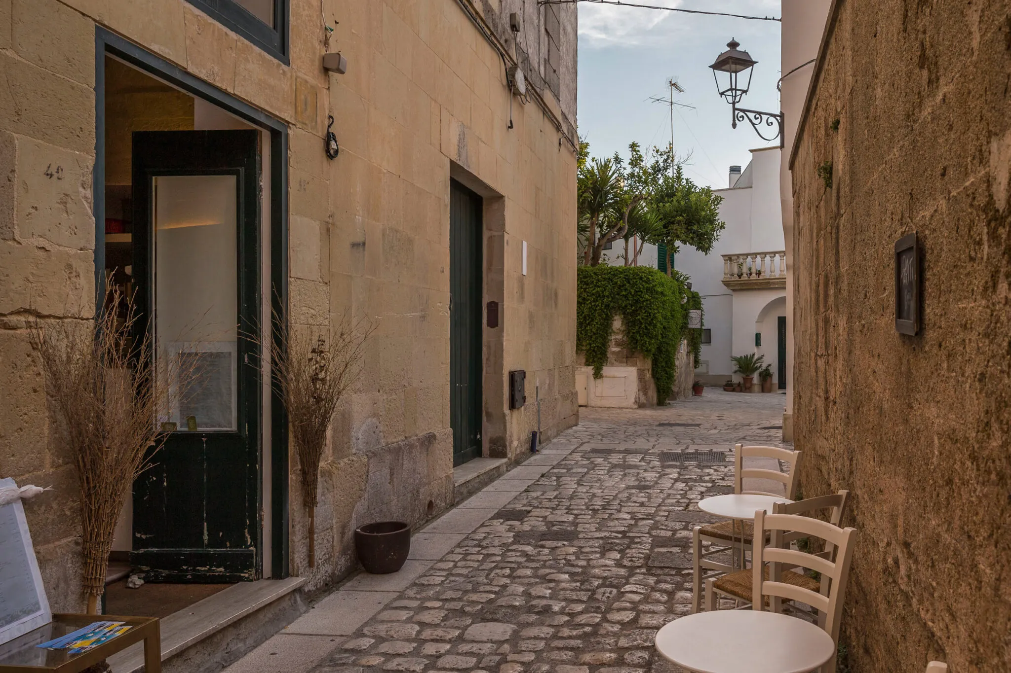 Chairs and tables on a stone walkway outside of a cafe