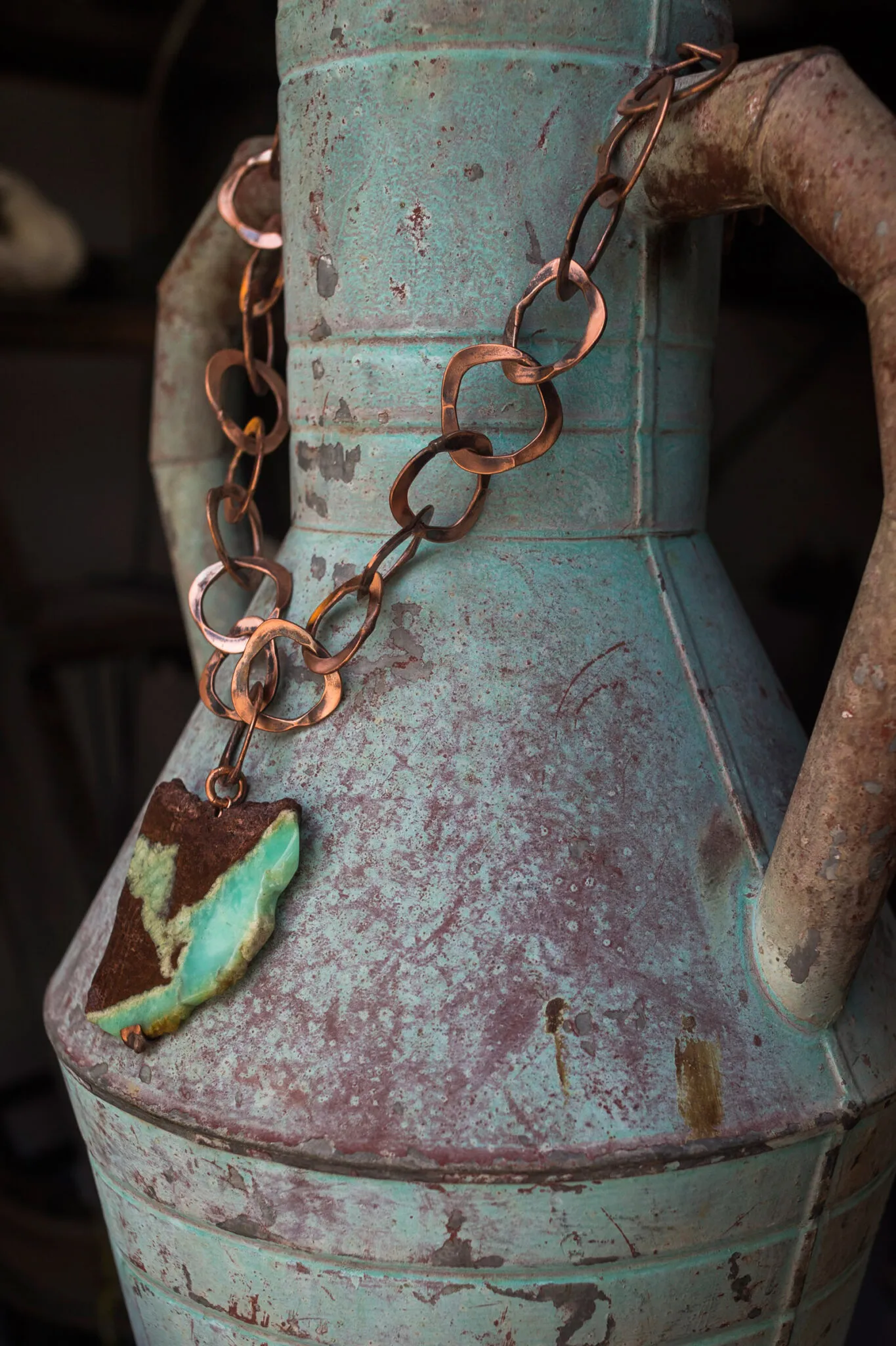 a stone and metal necklace displayed on a piece of pottery