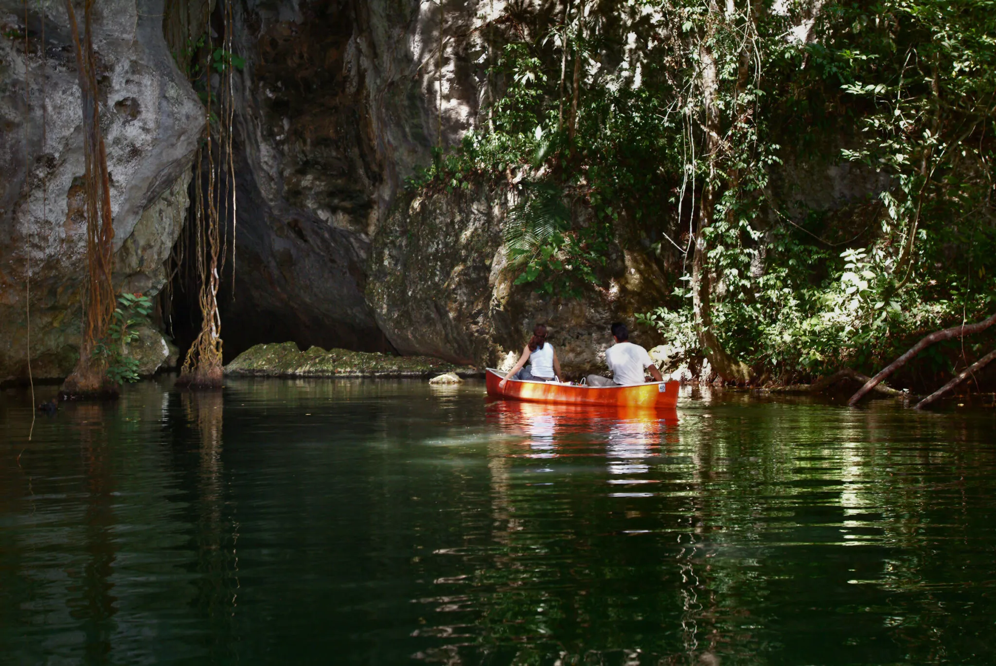 A couple in an orange canoe heads into a cave