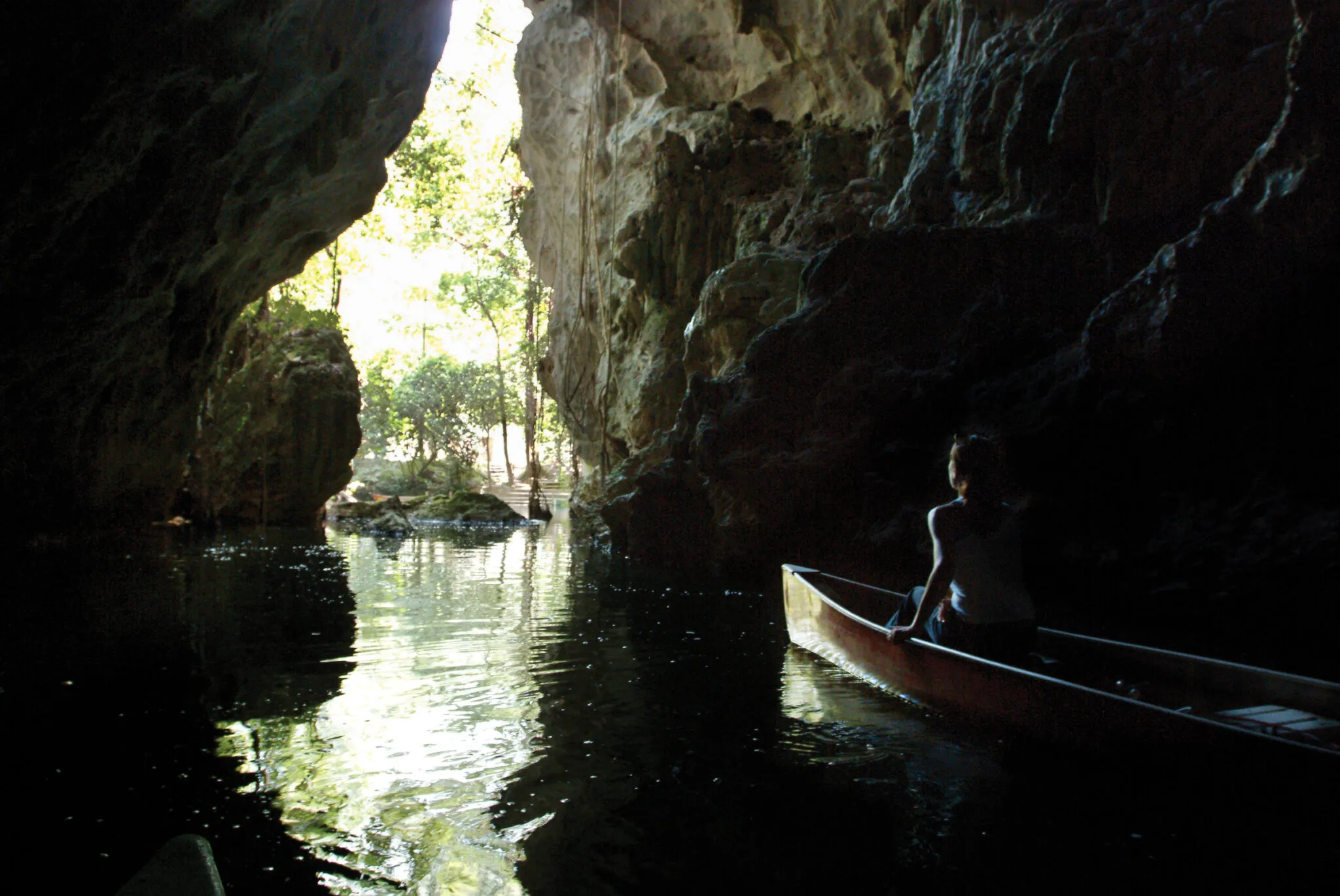 People in a canoe ooking out from the mouth of the cave