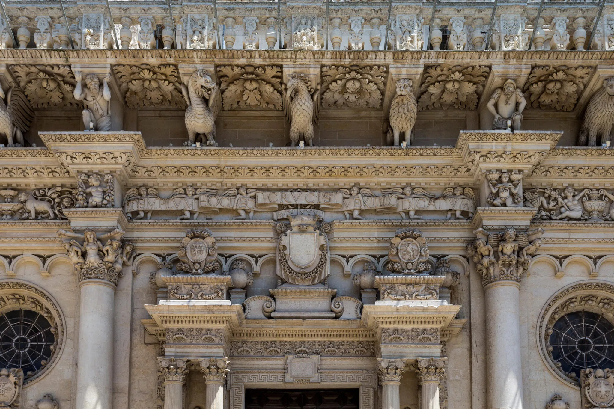 Intricate stone carvings of birds, gargoyles, cherubs and plants on a building facade