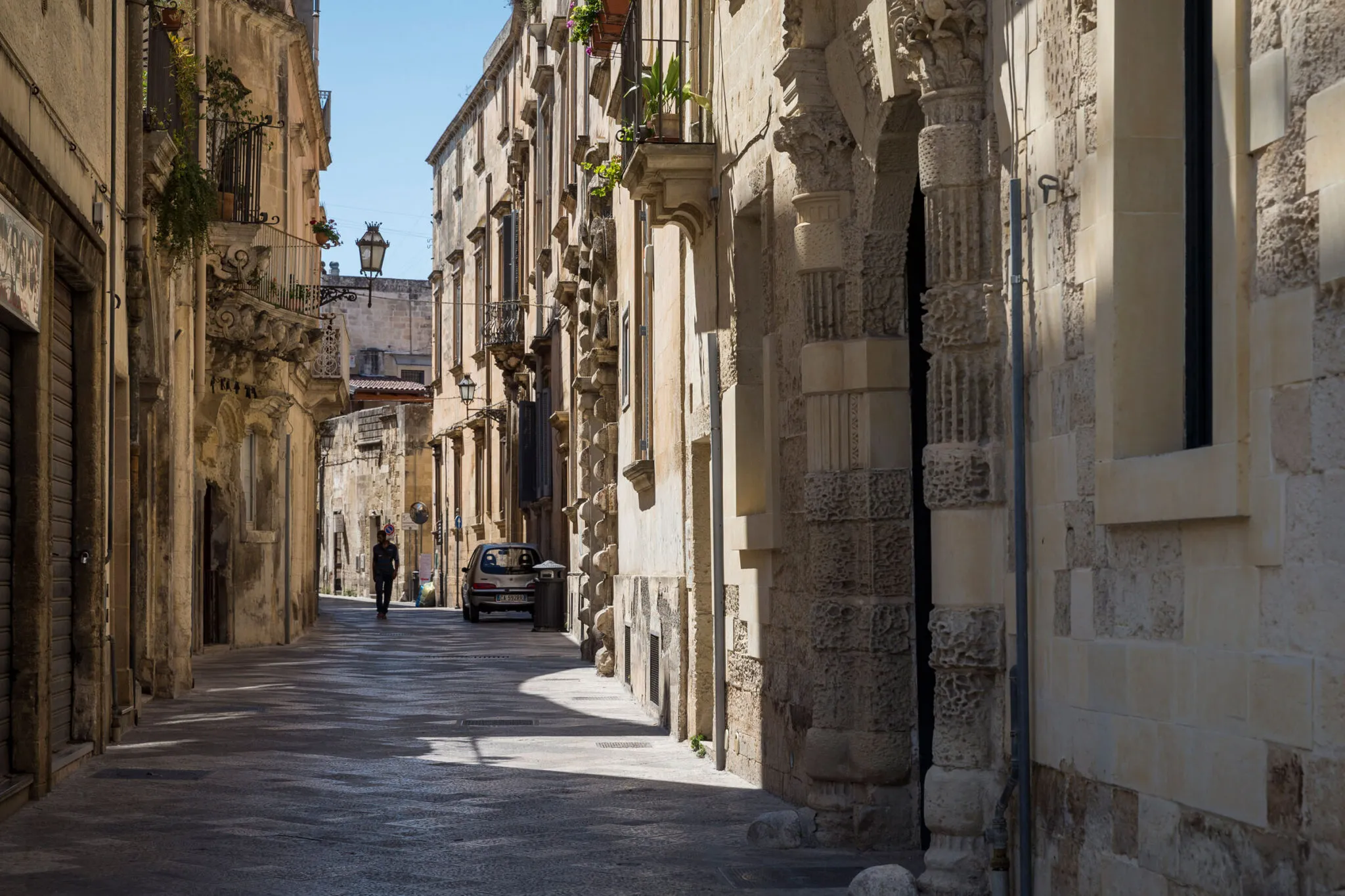 A man walks down a stone pathway between buildings