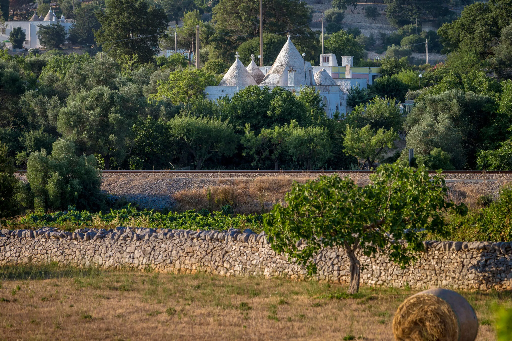 Stone wall with traintracks and homes with pointy roofs in the distance