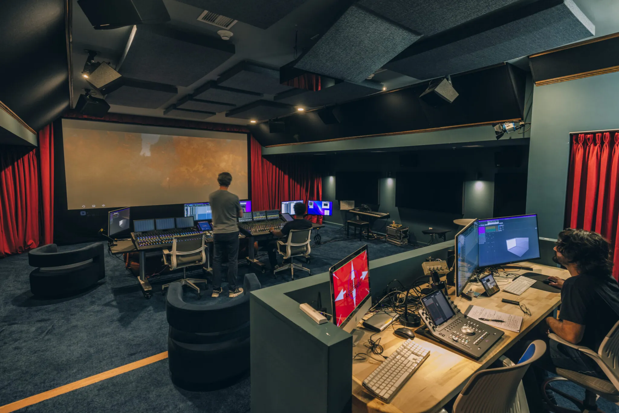 A man stands in the screening room while an editor works.