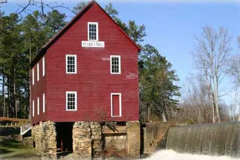 A mill building with a red exterior and windows with white trim.